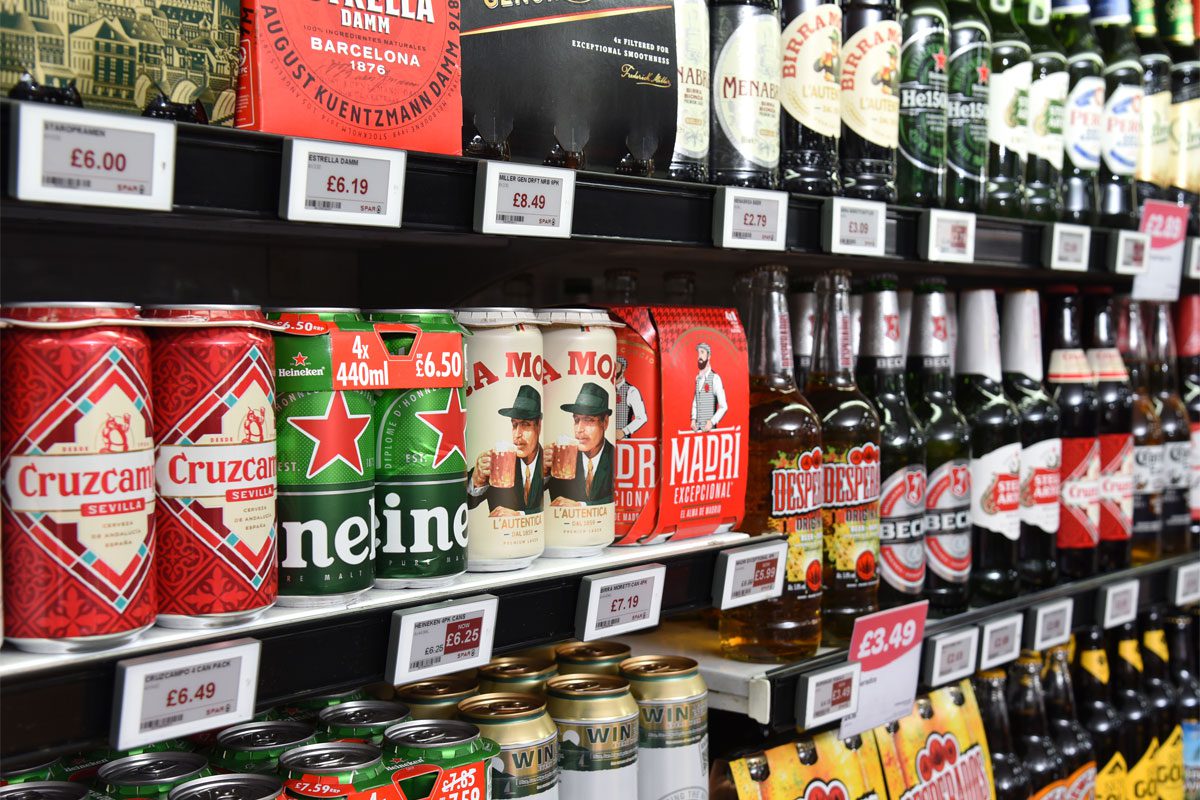 Bottles and cans of beers sit in a chiller in a store.