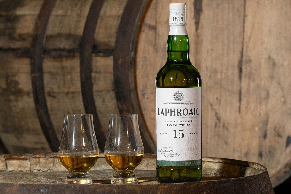 A bottle of Laphroaig 15 Year Old sits on a whisky barrel with two nosing glasses next to the bottle.