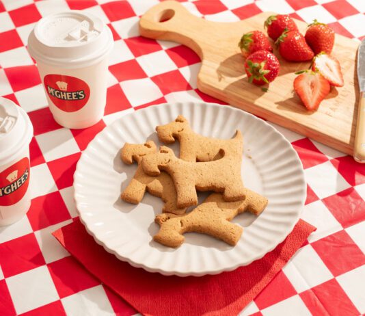 McGhee’s partners with Maggie’s with new Scottie biscuits A plate with McGhee's Scottie dog biscuits on it sits on a gingham blanket with coffee cups with McGhee's logo on them and a chopping board with cut up strawberries on them.