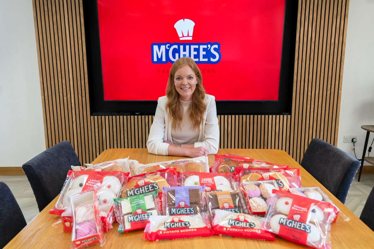 Aisling McGhee, commercial director at McGhee's, sits at a boardroom table with McGhee's products across the table.
