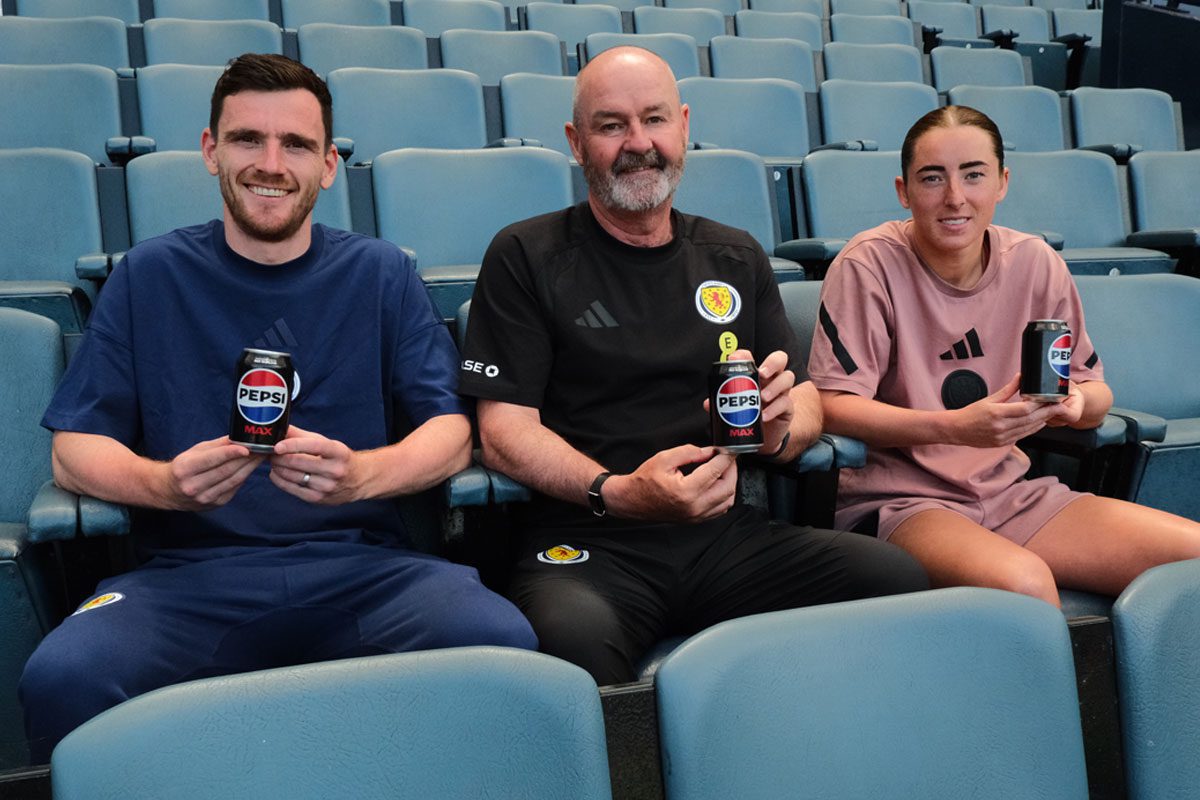 Scottish footballer Andy Robertson, Steve Clarke, head coach, and footballer Kathleen McGovern sit in Hampden Stadium seats holding cans of Pepsi Max.