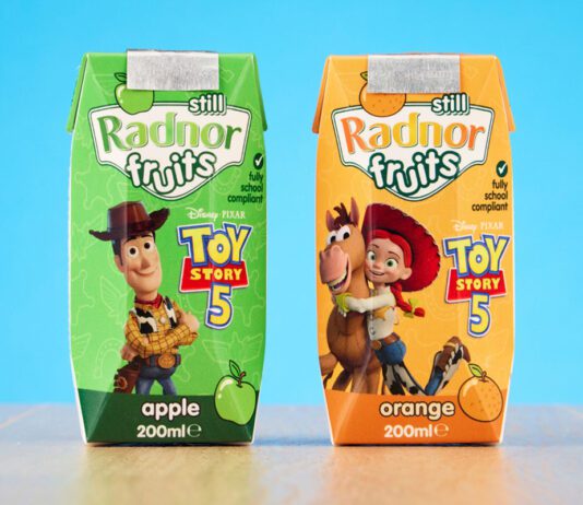 Radnor Hills unveils new Toy Story 5 collaboration Packs of Radnor Hills Toy Story 5 collaboration in Apple and Orange flavours, these are set against a blue background on top of a wooden table.