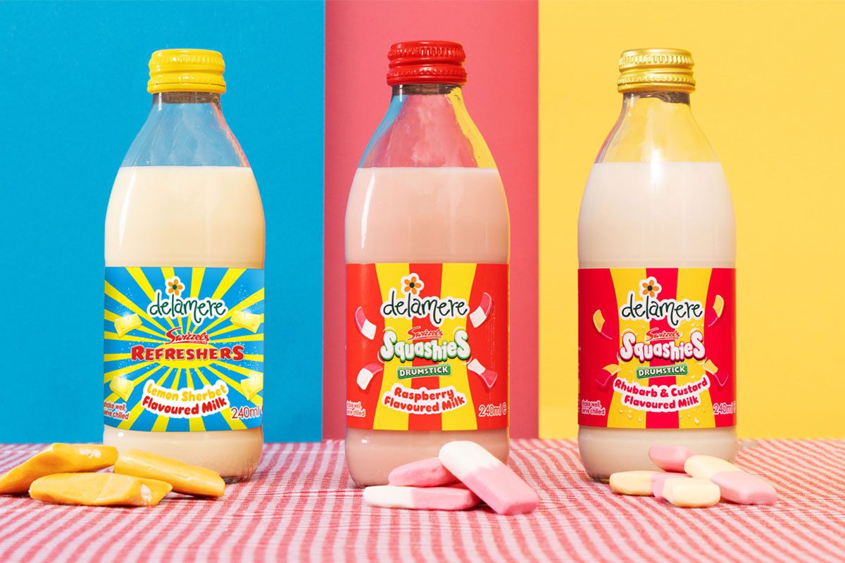 Bottles of Delamere Swizzels flavoured milks stand against different coloured background with the Swizzels sweets in front of the bottles.