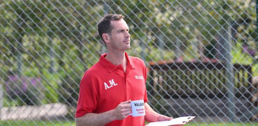Andy Murray steps into coach role in Walker’s Shortbread campaign Andy Murray stands in a tennis court holding a mug that says 'Walkers Spectator Coach' on it.