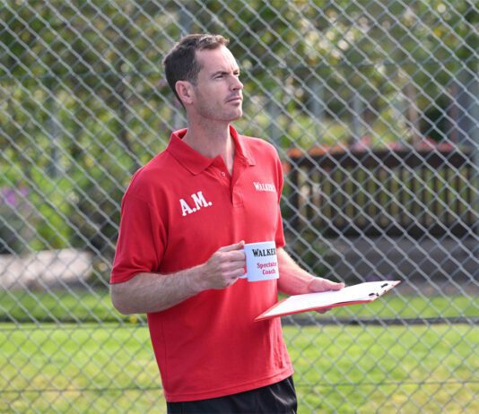 Andy Murray steps into coach role in Walker’s Shortbread campaign Andy Murray stands in a tennis court holding a mug that says 'Walkers Spectator Coach' on it.