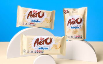 Nestlé unveils new Aero Milkybar range Packs of Aero Milkybar and Aero Milkybar Buttons are stacked on semi-circle shapes against a blue background with a white table.