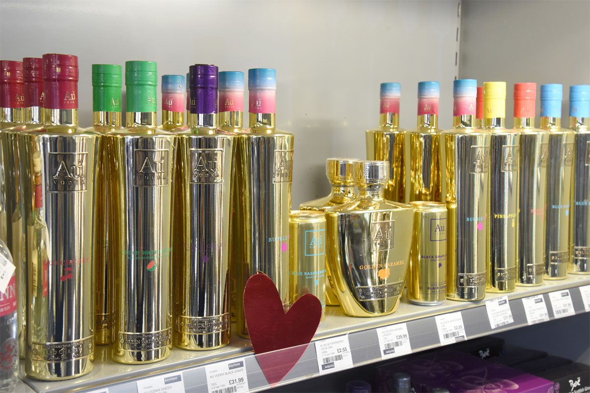 A store shelf with bottles of Au Vodka across it.