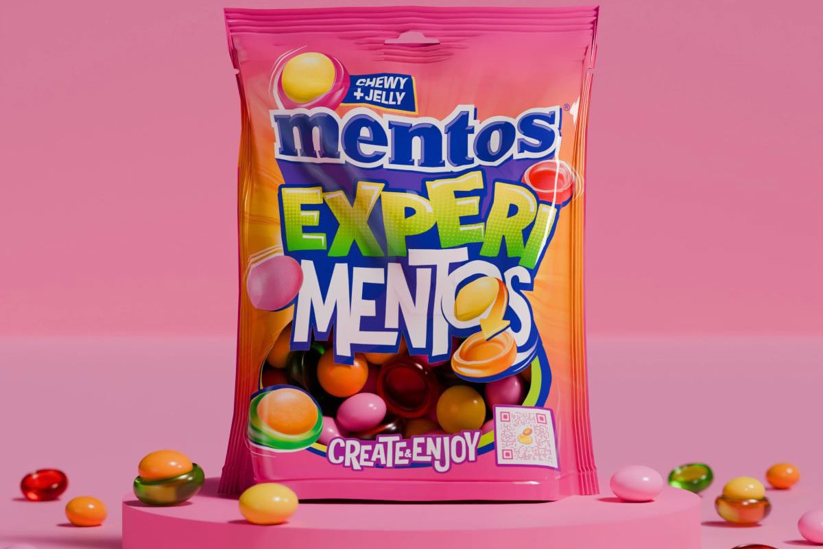 A bag of Mentos Experimentos sits against a pink background with some of the sweets around the bag.