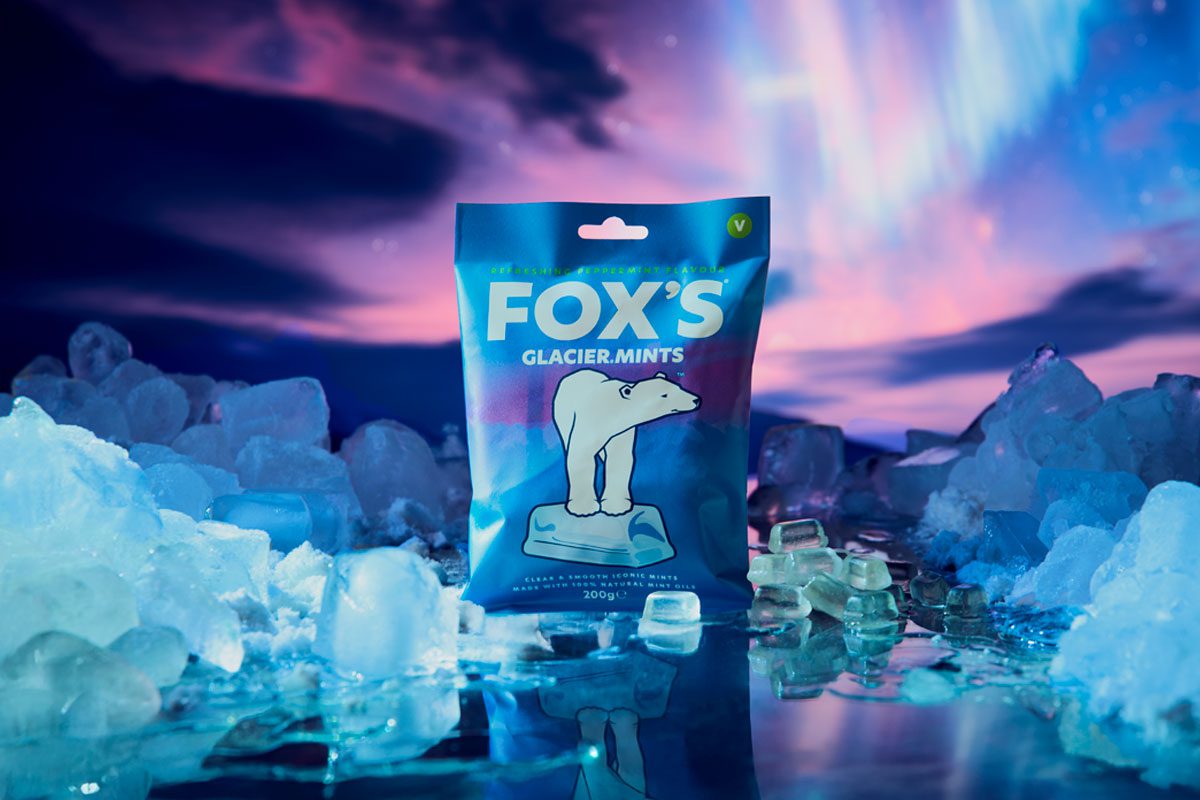 A pack of Fox's Glacier Mints stands in an arctic scene with the Northern Lights behind it.