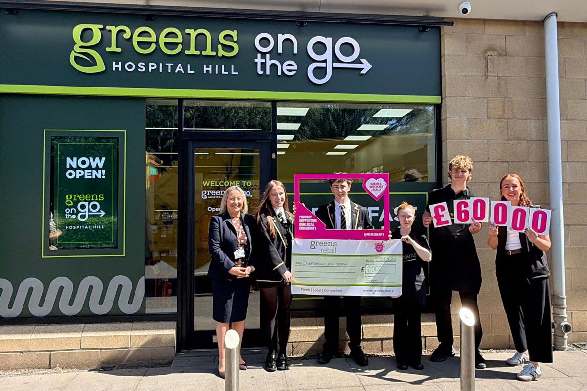 A group of children from Dunfermline High School stand outside Green's On The Go Hospital Hill holding signs and a cheque for £1,000.