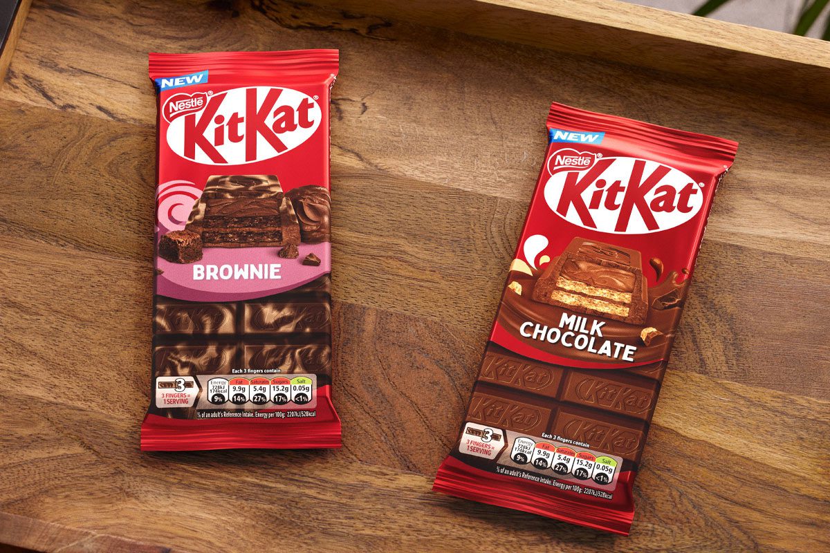 Packs of KitKat Sharing Bars Brownie and Milk Chocolate flavour sit on a wooden tray.