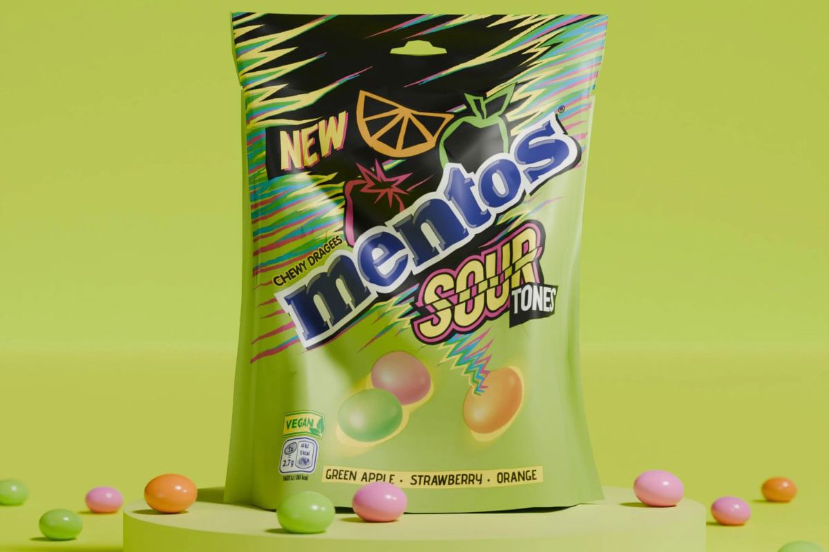 A pack of Mentos Sour Tones Sharing Pack stands against a lime green background with some of the sweets scattered around the bag.