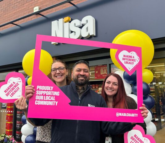 Co-op hits £20million milestone on charity donations A group of people stand outside a Nisa store with a Making a Difference Locally banner around them.