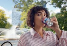 Pepsi launches summer campaign for ice cream flavours A woman sits drinking from a can of Pepsi Cherry & Vanilla Flavour in a park.
