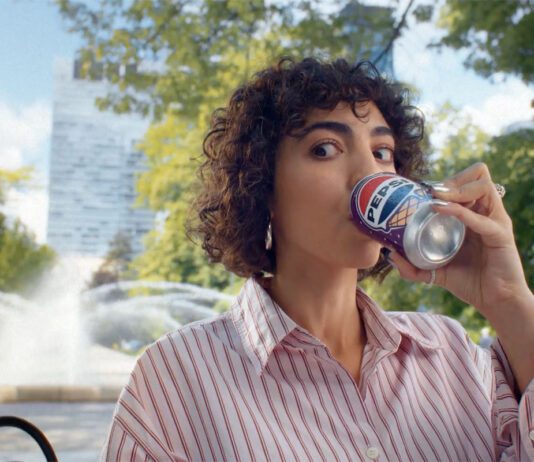 Pepsi launches summer campaign for ice cream flavours A woman sits drinking from a can of Pepsi Cherry & Vanilla Flavour in a park.