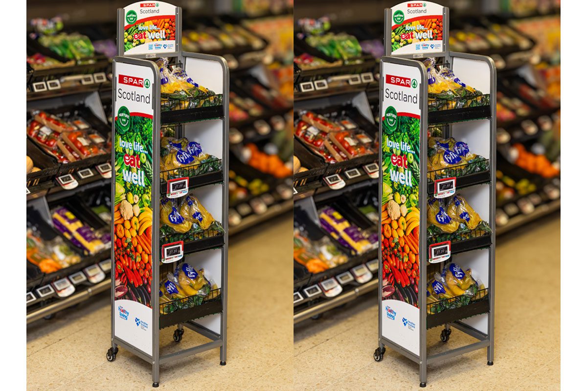 An image of the Spar Scotland Healthy Living Programme dual-branded standing unit with shelves of fruit and veg behind the stands.