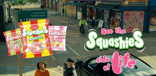 Swizzels pushes Squashies range in new TV ad campaign A still image from the 'See the Squashies side of life' ad campaign for Swizzels with a woman walking down a street with inflatable characters near her. Packs of Swizzels Squashies variants are also included in the imagery.