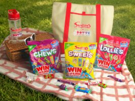 Swizzels launches Day Out With The Kids promo packs A picnic scene with variety packs of Swizzels sweets, a picnic blanket, a basket, sunglasses, a water bottle and an insulated bag with the Swizzels and Day Out With The Kids logo on the front of it.