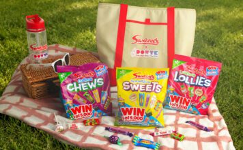 Swizzels launches Day Out With The Kids promo packs A picnic scene with variety packs of Swizzels sweets, a picnic blanket, a basket, sunglasses, a water bottle and an insulated bag with the Swizzels and Day Out With The Kids logo on the front of it.