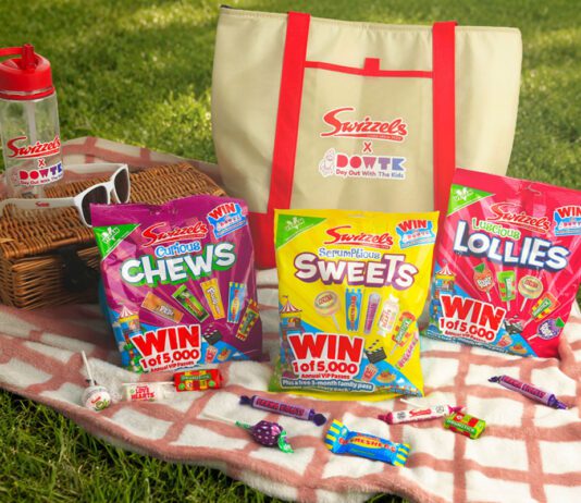 Swizzels launches Day Out With The Kids promo packs A picnic scene with variety packs of Swizzels sweets, a picnic blanket, a basket, sunglasses, a water bottle and an insulated bag with the Swizzels and Day Out With The Kids logo on the front of it.