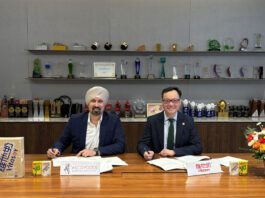 Asco Foods gains distribution for Vitasoy Representatives from Asco Foods and Vitasoy sit at a table signing a new distribution deal between the two firms.