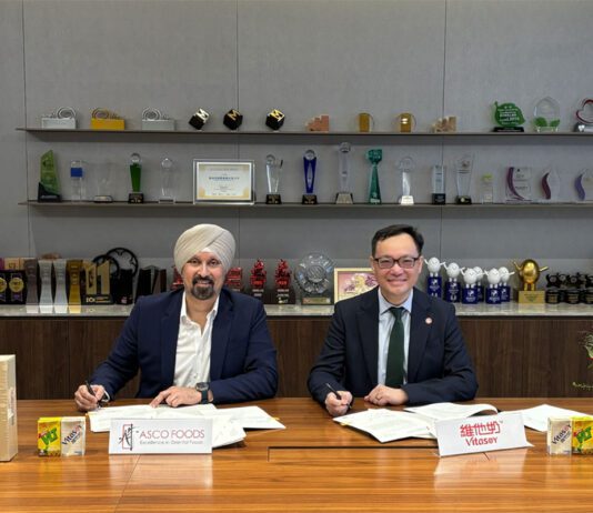 Asco Foods gains distribution for Vitasoy Representatives from Asco Foods and Vitasoy sit at a table signing a new distribution deal between the two firms.