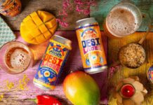 Curry Smugglers launches new Desi Beer brand Cans of Desi Lager Basmati Rice Lager and alcohol-free Mango Mirchi Lager lay on a table with food ingredients around it and glasses with the beers poured into them.