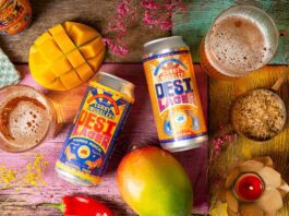 Curry Smugglers launches new Desi Beer brand Cans of Desi Lager Basmati Rice Lager and alcohol-free Mango Mirchi Lager lay on a table with food ingredients around it and glasses with the beers poured into them.
