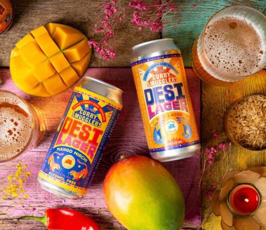 Curry Smugglers launches new Desi Beer brand Cans of Desi Lager Basmati Rice Lager and alcohol-free Mango Mirchi Lager lay on a table with food ingredients around it and glasses with the beers poured into them.