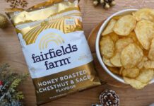 Fairfields Farm brings back popular Christmas crisps A pack of Fairfields Farm Honey Roasted Chestnut & Sage crisps sits next to a bowl with crisps in it with some Christmas decorations around the two.