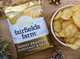 Fairfields Farm brings back popular Christmas crisps A pack of Fairfields Farm Honey Roasted Chestnut & Sage crisps sits next to a bowl with crisps in it with some Christmas decorations around the two.