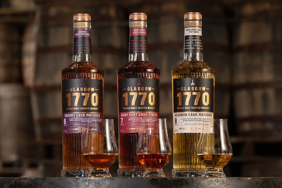 Bottles of Glasgow 1770 Batch 2 sit on a barrel with nosing glasses in front of them with samples of the whiskies inside. (L to R) Glasgow 1770 Sherry Cask Matured, Glasgow 1770 Ruby Port Cask Finish and Glasgow 1770 Bourbon Cask Matured.