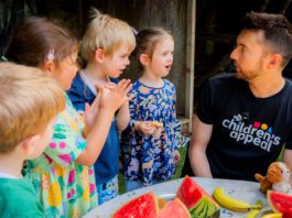 Kellogg’s teams up with STV’s Big Scottish Breakfast STV presenter Sean Batty sits at a table with fruit on it talking to a group of children.
