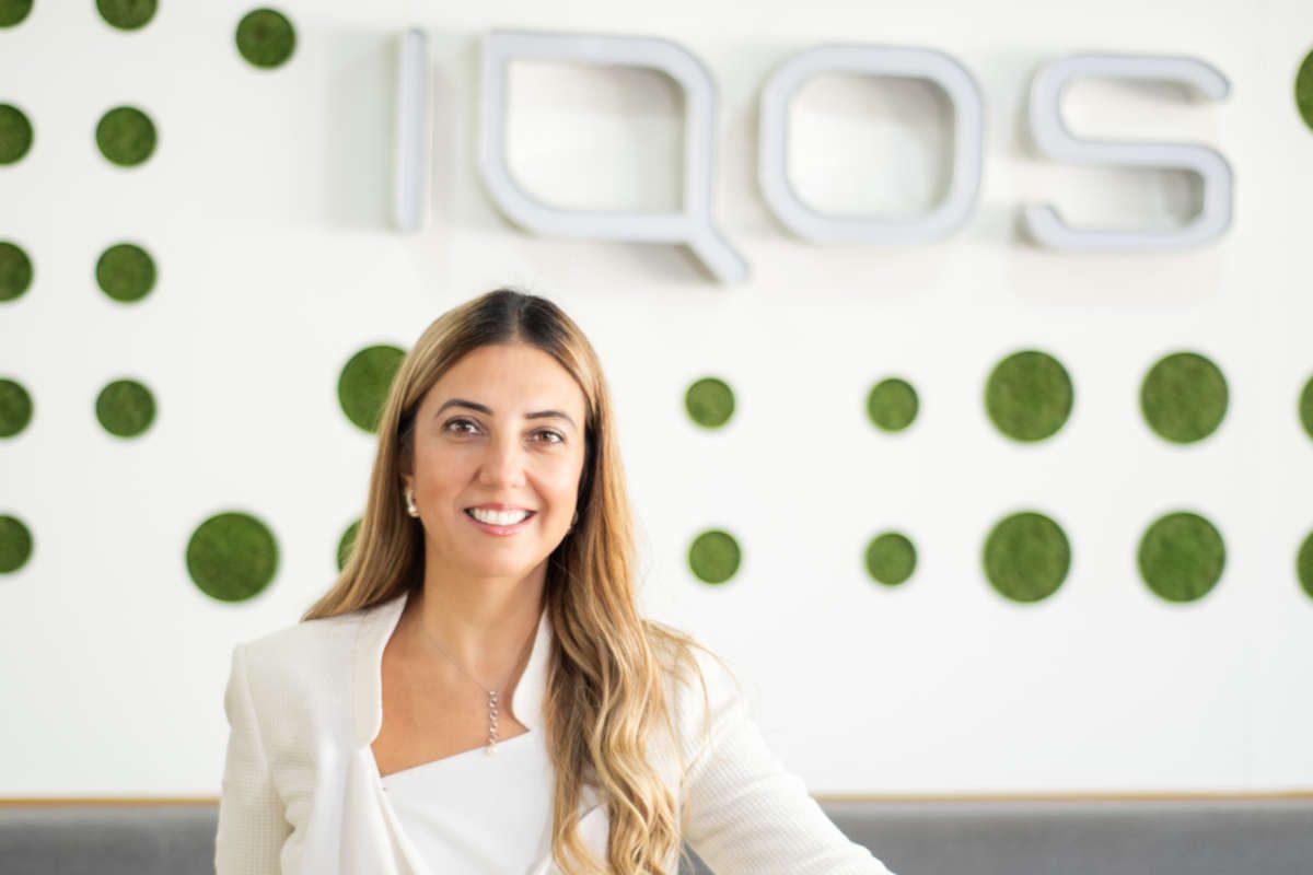 Bahar Demirci, senior director of smoke-free products at Philip Morris Limited, stands in front of the IQOS logo.