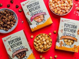 Popcorn Kitchen unveils Christmas gifting range Packs of Popcorn Kitchen Christmas gift packs lie across a red tabletop with bowls of the popcorn around them. The flavorus include White Choc & Raspberry, Double Choc Caramel Cookie and Gingerbread.