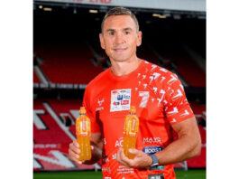 Boost announces sponsorship of Sinfield’s 7-in-7 fundraiser Sir Kevin Sinfield stands holding bottles of Boost Sport drinks while standing in Old Trafford stadium.