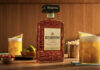 Disaronno unveils new bottle design A bottle of the 2026 redesign for Disaronno stands on a table with Amaretto Sour cocktail serves around it as well as bowls of nibbles.
