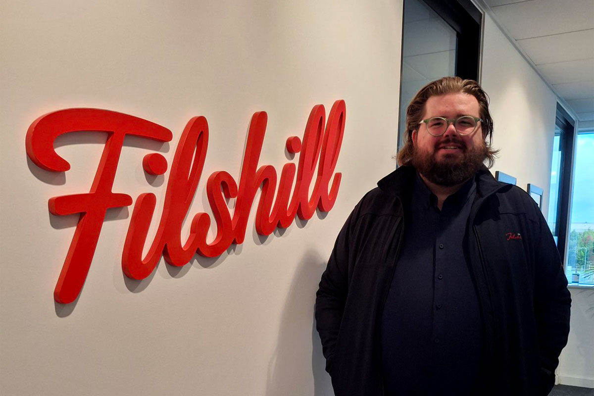 Scott Sutherland, regional development manager at JW Filshill, stands next to the Filshill logo at the company's offices.
