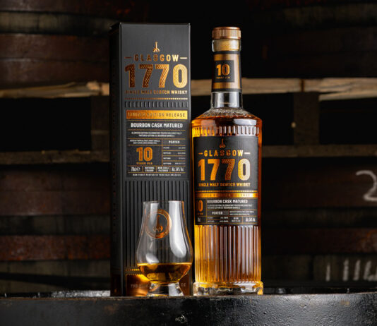 Glasgow 1770 unveils first 10 Year Old peated malt A bottle of Glasgow 1770 10 Year Old Peated Single Malt Scotch Whisky stands on a barrel with its outer packaging next to it with a nosing glass with the whisky inside.