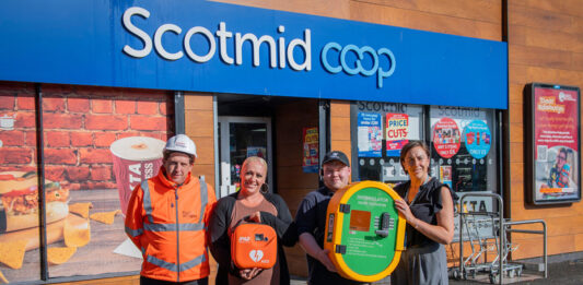 Taylor Wimpey donates defibrillator to Scotmid A group of people stand outside Scotmid Ratho Station holding a defibrillator device that is to be installed on the store's exterior wall.