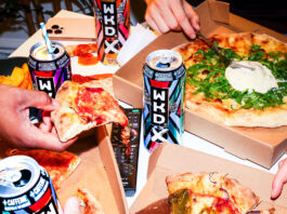 Find a ‘WKD Side’ for Freshers and Halloween A group of people are taking slices of pizza from different boxes with cans of WKDX around the boxes.