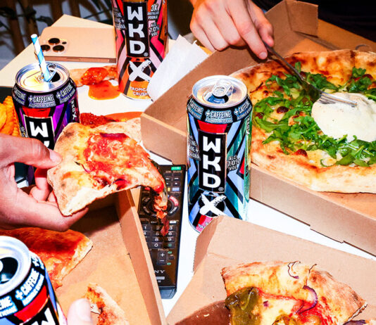 Find a ‘WKD Side’ for Freshers and Halloween A group of people are taking slices of pizza from different boxes with cans of WKDX around the boxes.