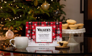 Walker’s sets out Christmas range for 2026 A pack of Walker's Luxury Mince Pies sits on a table with a mug next to it and one of the mince pies to the other side of it. In the background, the pies are stacked up on a table and there is a Christmas tree.