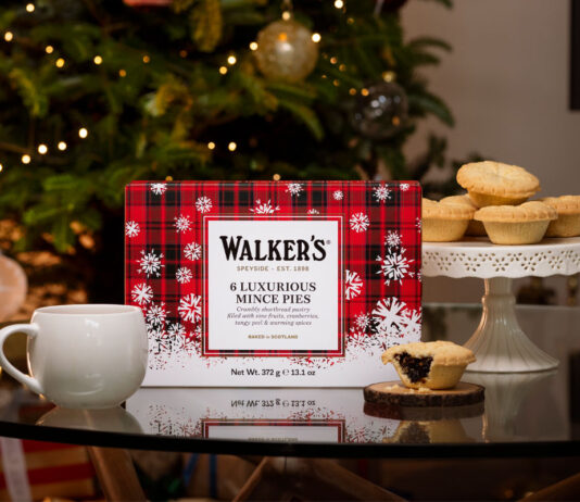 Walker’s sets out Christmas range for 2026 A pack of Walker's Luxury Mince Pies sits on a table with a mug next to it and one of the mince pies to the other side of it. In the background, the pies are stacked up on a table and there is a Christmas tree.