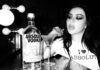 Absolut Vodka teams up with Charli XCX Pop star Charli XCX sits at a dressing table with a Dirty Martini cocktail serve next to a bottle of Absolut Vodka. The photo is in black and white.