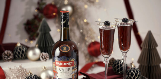 Bardinet rolls out limited edition design for Christmas A bottle of Bardinet VSOP stands on a table with two cocktail serves next to it. There is a range of Christmas decorations across the table as well.