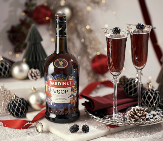 Bardinet rolls out limited edition design for Christmas A bottle of Bardinet VSOP stands on a table with two cocktail serves next to it. There is a range of Christmas decorations across the table as well.