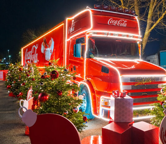 Vote opens for Coca-Cola Christmas truck’s next stop The Coca-Cola Christmas Truck is parked up with lighting around its edges and decorative Coca-Cola branded Christmas decorations around it.