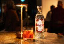 Eden Mill unveils Winter gin for Negroni cocktails A bottle of Eden Mill Winter in St Andrews gin stands on a table with a Negroni cocktail serve next to it and a lamp.