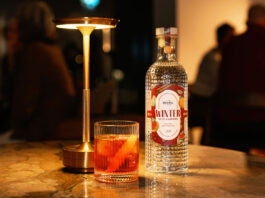 Eden Mill unveils Winter gin for Negroni cocktails A bottle of Eden Mill Winter in St Andrews gin stands on a table with a Negroni cocktail serve next to it and a lamp.